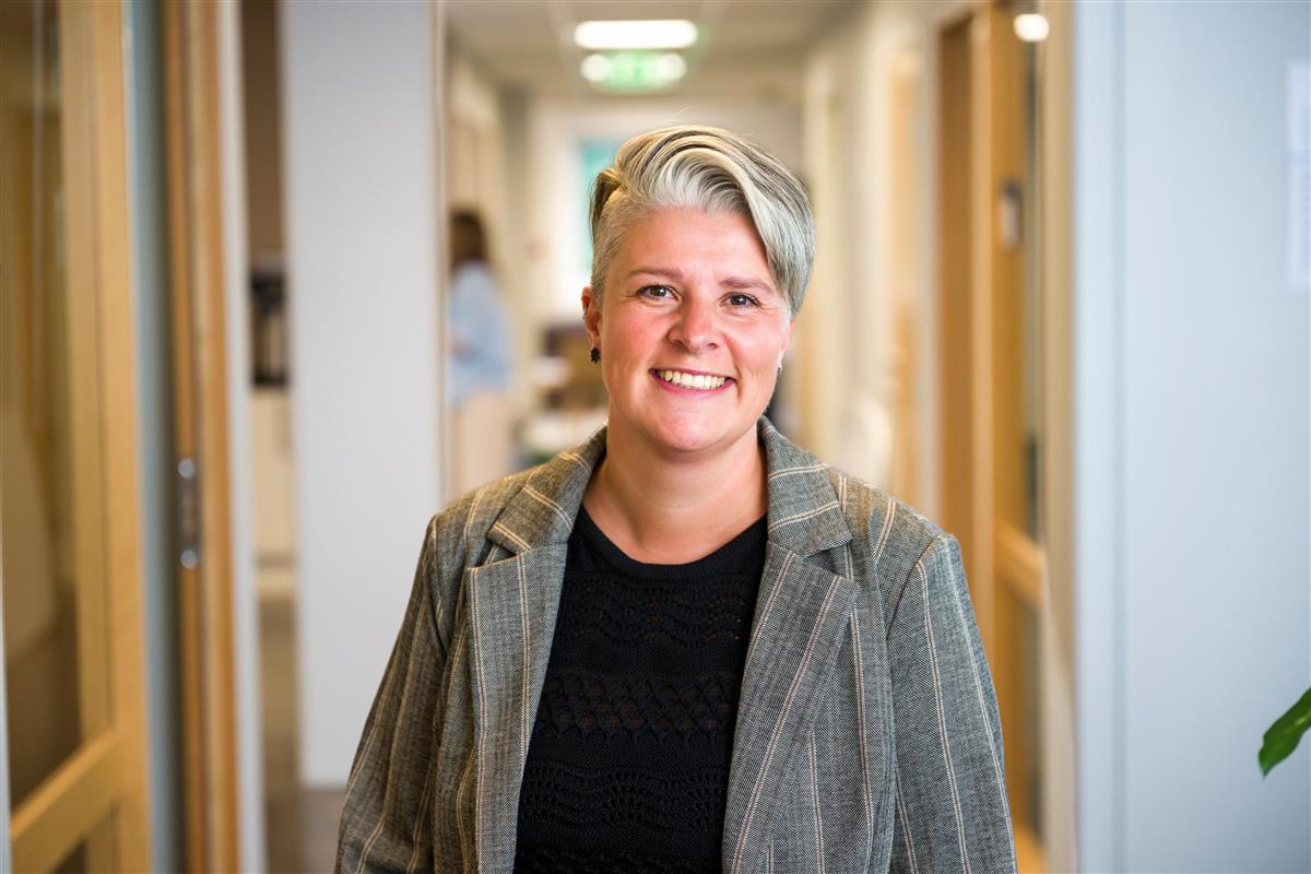 Portrett av kvinne med lyst, kort h&aring;r som ser inn i kamera.