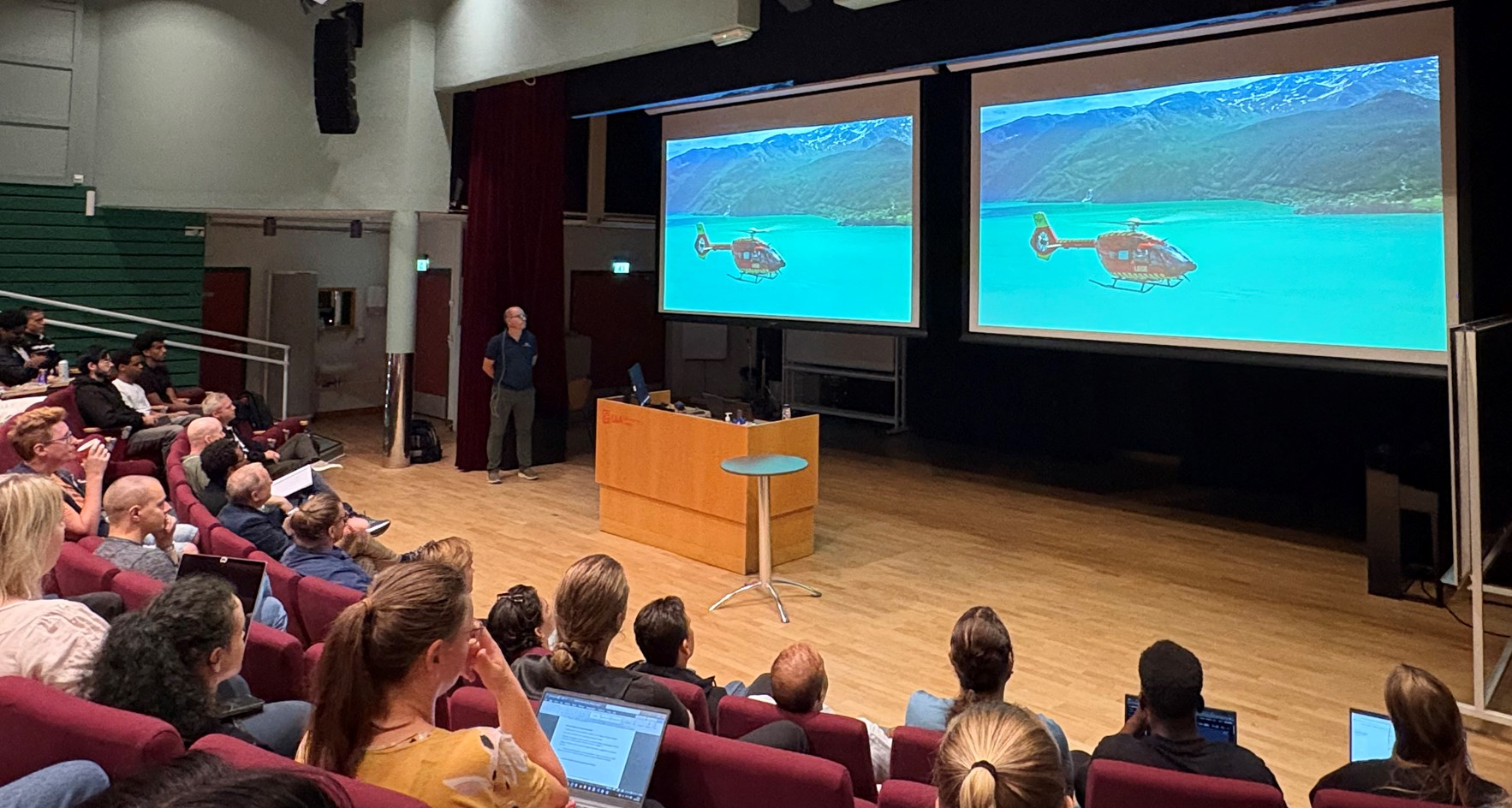 Ansatt i Norsk luftambulanse foran en klasse i en forelesningssal mens han viser animasjonsfilm av helikopter