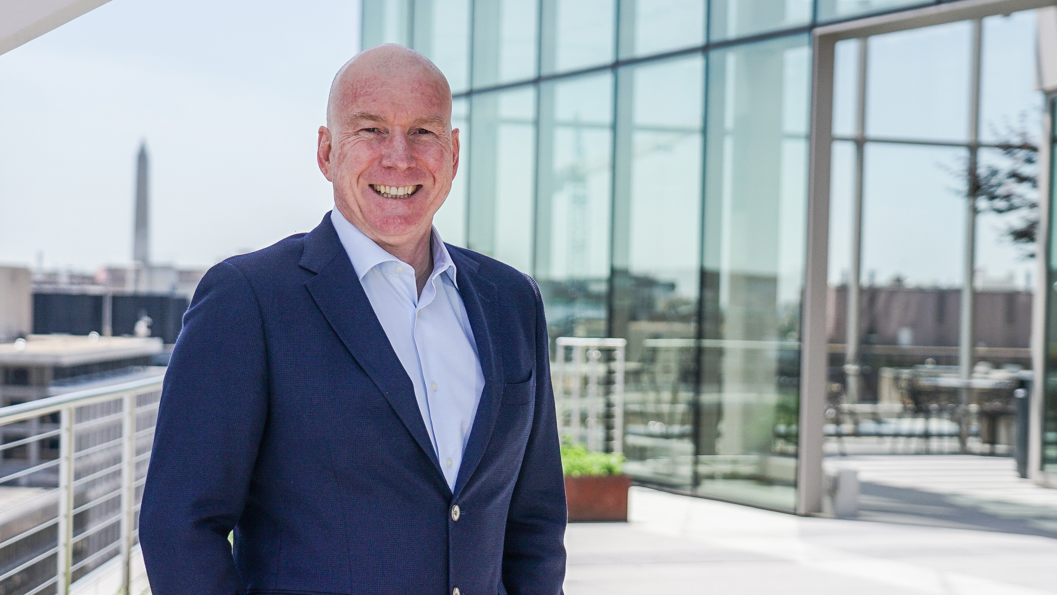 Smilende mann ikledt dress og bl&aring; skjorte.