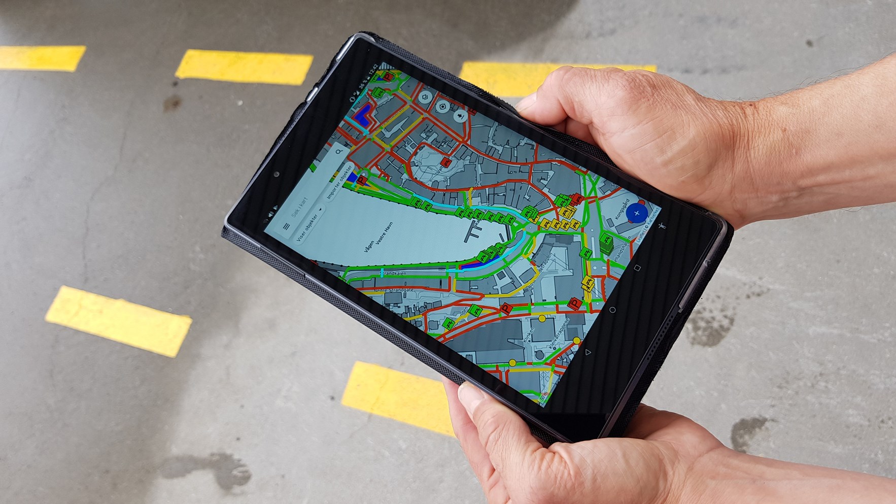 Hender holder et nettbrett hvor en kartapp med tilgjengelighetsdata vises