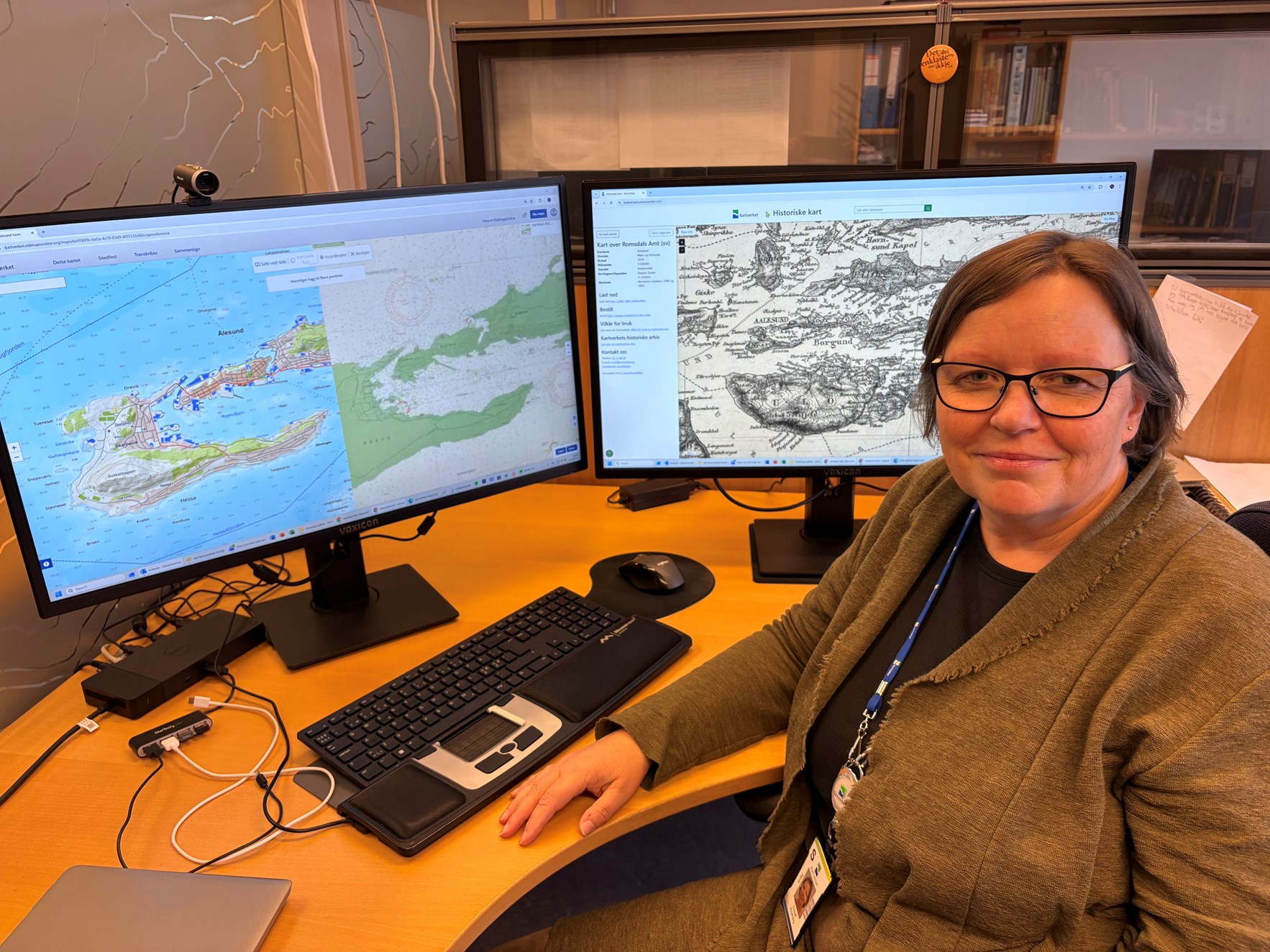 Kvinnelig ansatt i Kartverket foran en PC-skjerm med gamle kart