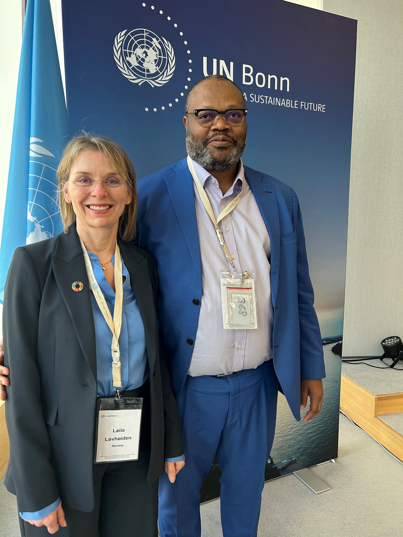 Kvinne og mann foran et FN-flagg med p&aring;skriften UN Bonn