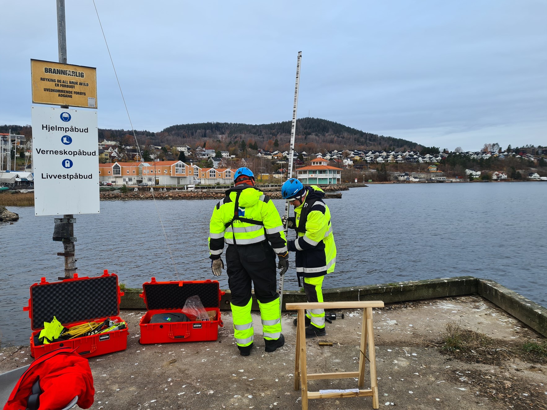 To arbeidere fra Kartverket monterer vannstandsm&aring;ler p&aring; brygge i Drammen