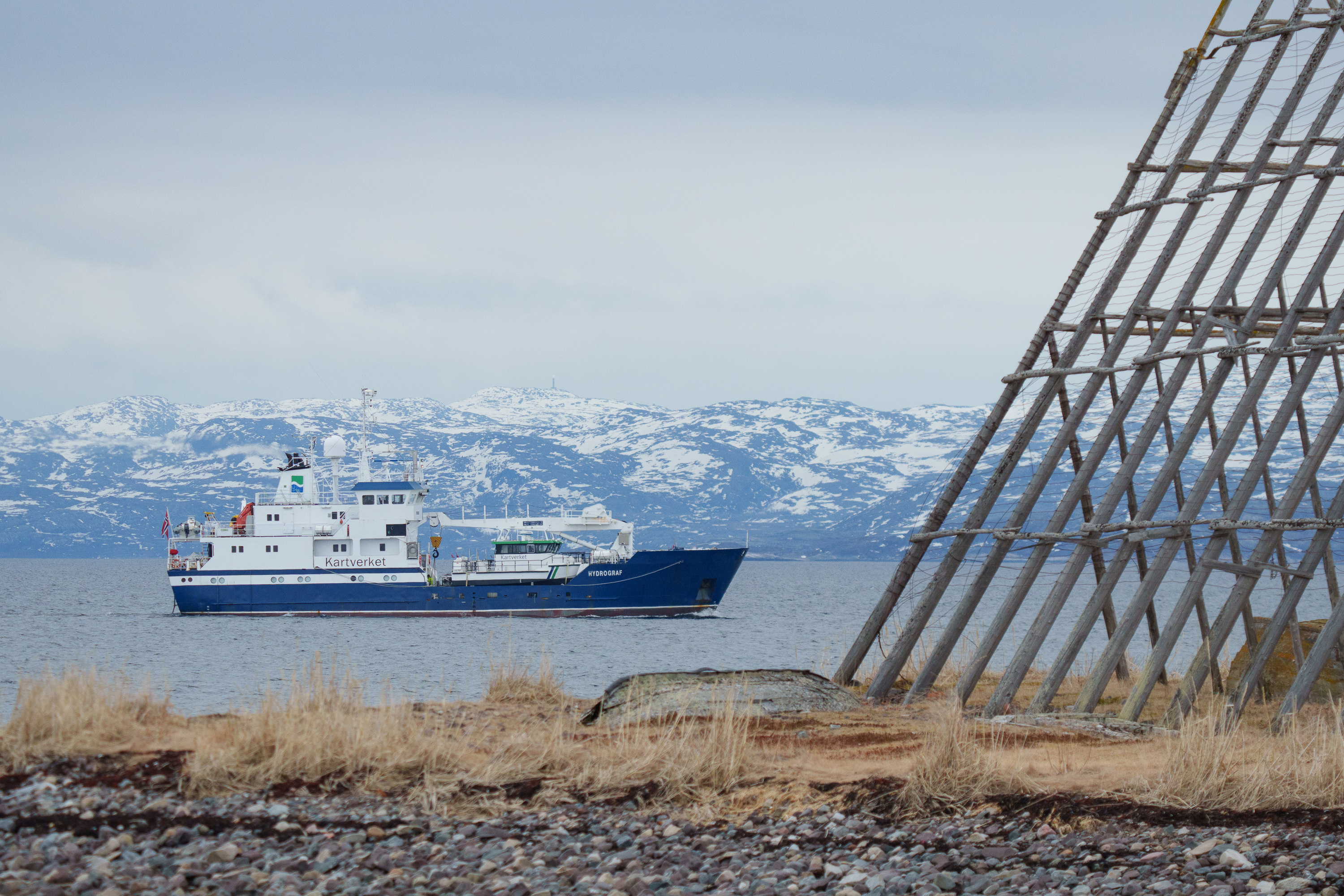 Kartverkets m&aring;leskip Hydrograf i Varangerfjorden, med fiskehjell i forgrunnen og sn&oslash;dekte fjell i bakgrunnen.