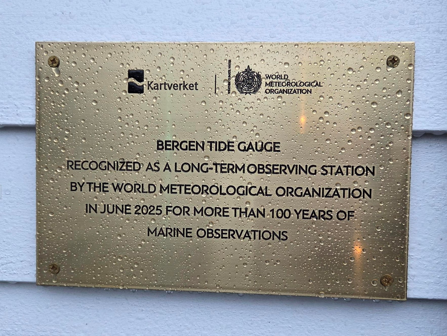 Plakett med logo en til Kartverket og WMO. P&aring; plaketten st&aring;r det Bergen Tide Gauge recognized as a long-term observing statison by the world meteorolgical organization in june 2025 for more than 100 years of marine observations.