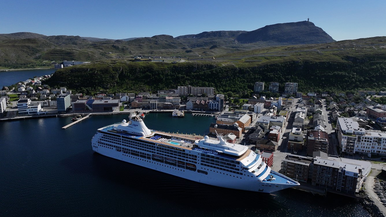 Oversiktsbilde av Hammerfest by hvor et st&oslash;rre fart&oslash;y ligger fort&oslash;yd ved sentrumskaien.