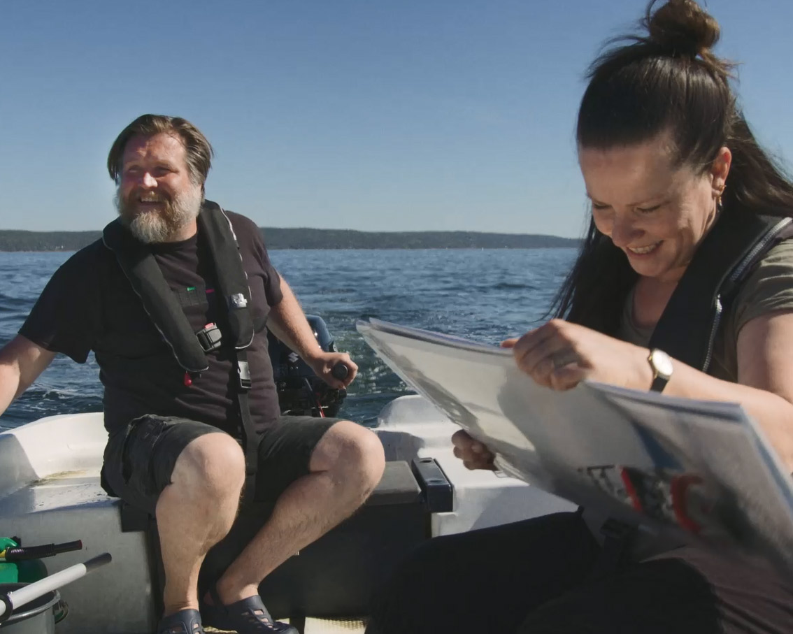 Mann styrer motorbåt mens dame sjekker sjøkartet. Foto: Kartverket