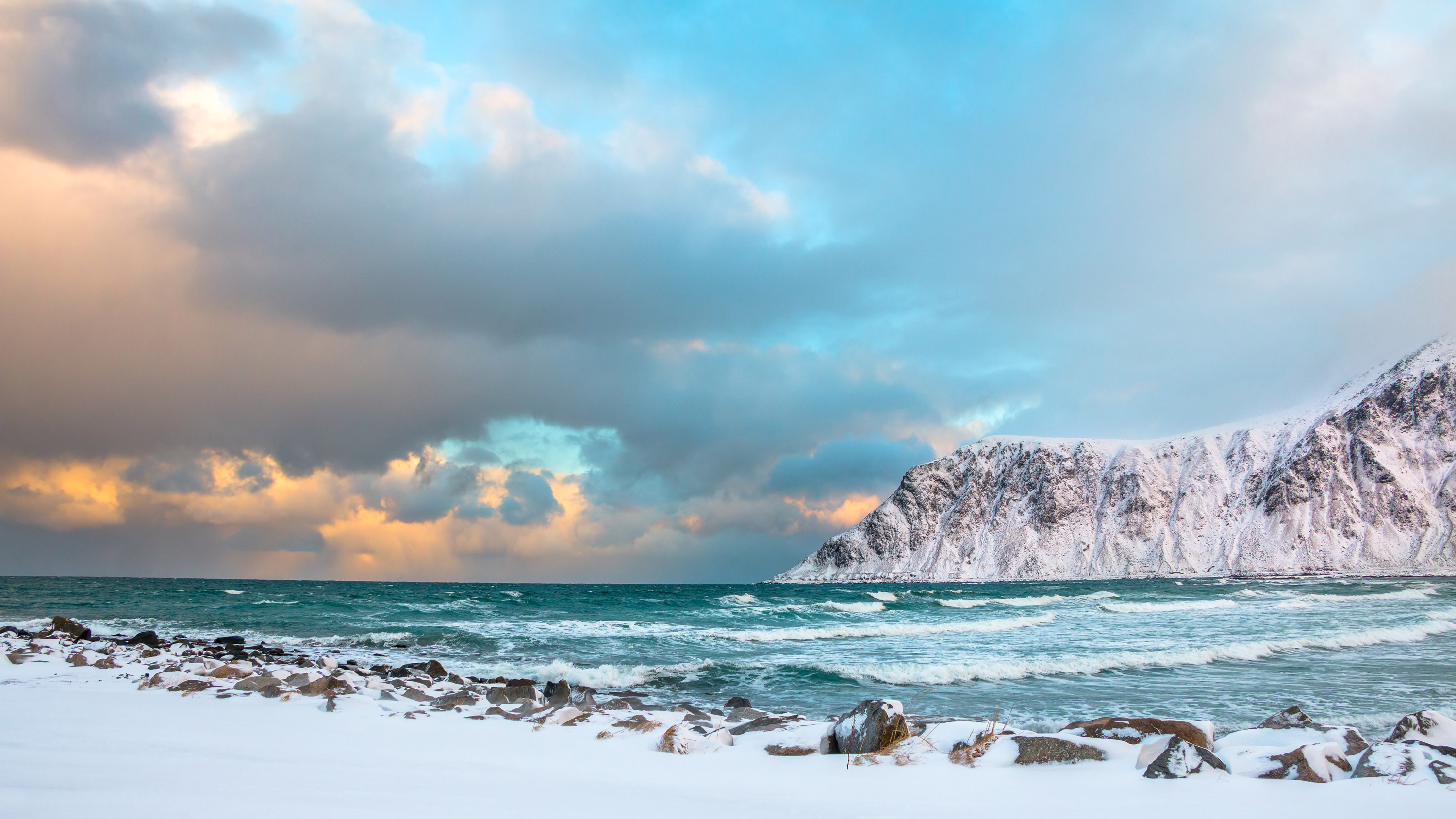 Vintermorgen på en strand i Lofoten. Det er lavvann og bølger slår mot land. Foto: Mostphotos
